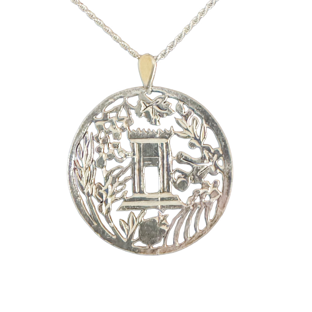 Silver pendant with intricate design on a white background